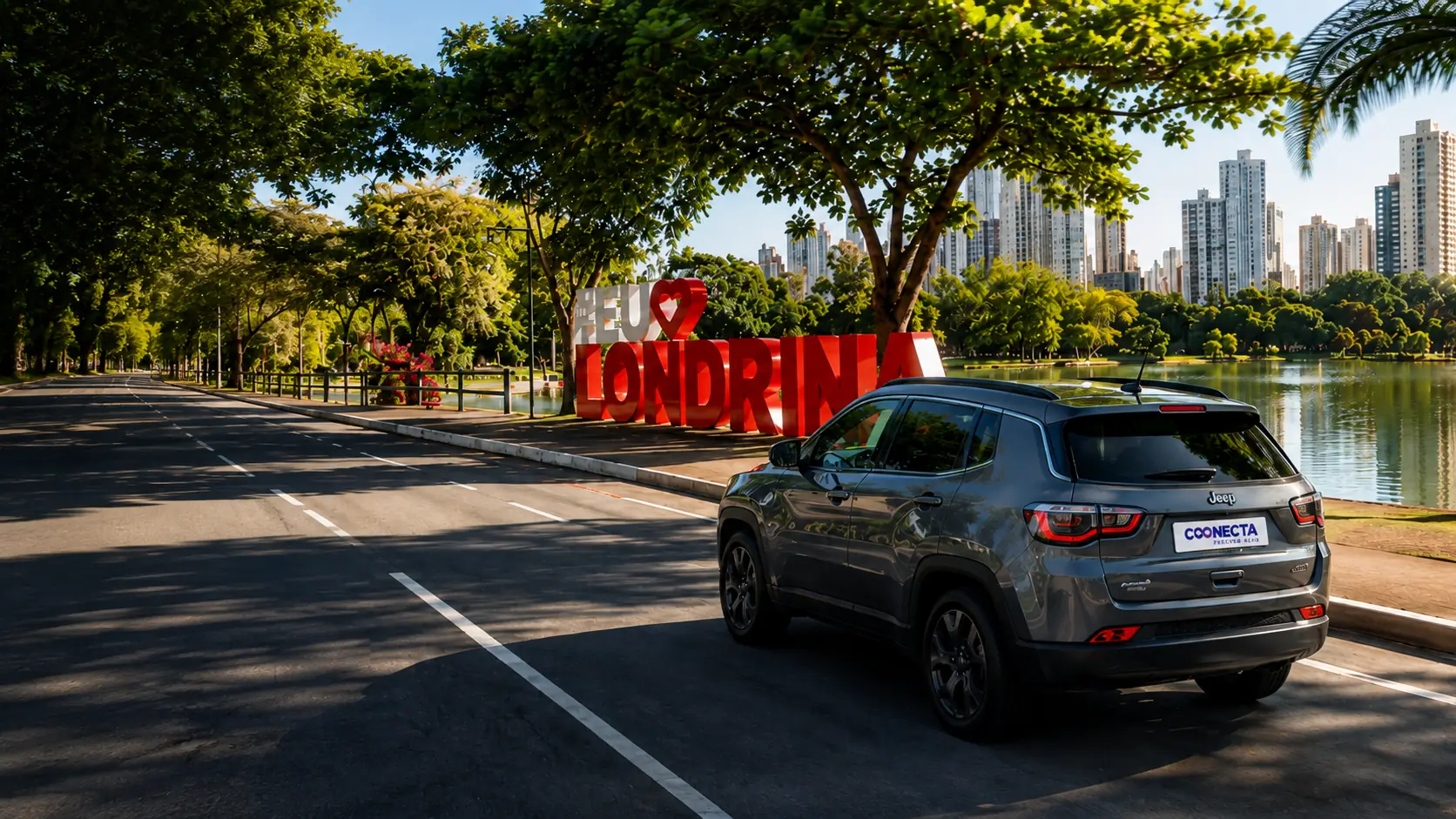 SUV da Coonecta em frente ao letreiro Eu Amo Londrina, à beira do Lago Igapó com o skyline da cidade ao fundo